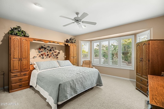 bedroom with multiple windows, light colored carpet, baseboards, and a ceiling fan