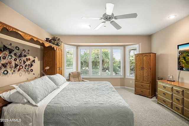 bedroom featuring light colored carpet, baseboards, ceiling fan, and multiple windows