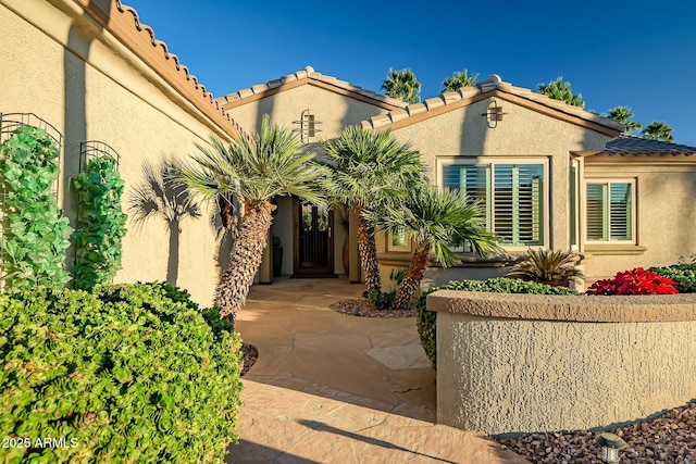 view of exterior entry featuring stucco siding and a tiled roof