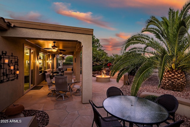 view of patio / terrace with outdoor dining space, a ceiling fan, and an outdoor fire pit