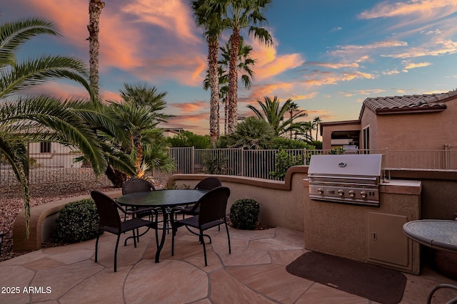 view of patio with outdoor dining space, exterior kitchen, fence, and a grill