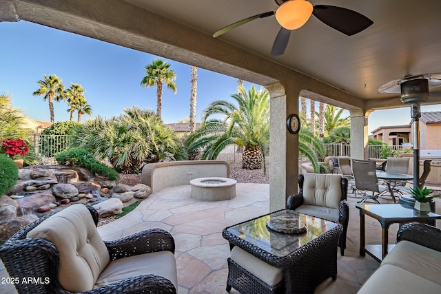 view of patio / terrace featuring ceiling fan, an outdoor living space with a fire pit, a fenced backyard, and outdoor dining space