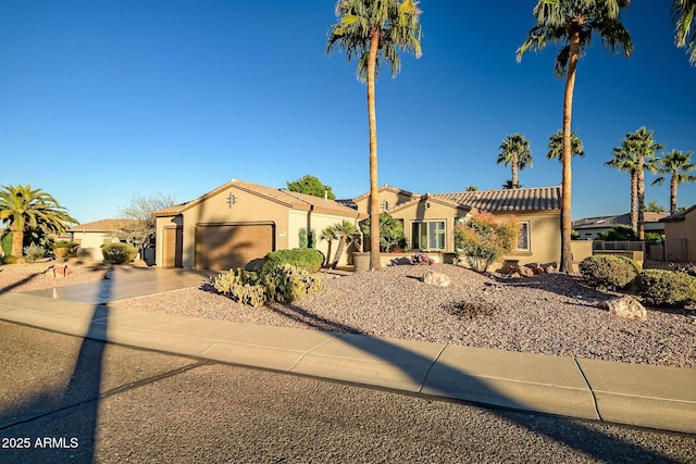 mediterranean / spanish-style house featuring a garage, a tile roof, driveway, and stucco siding