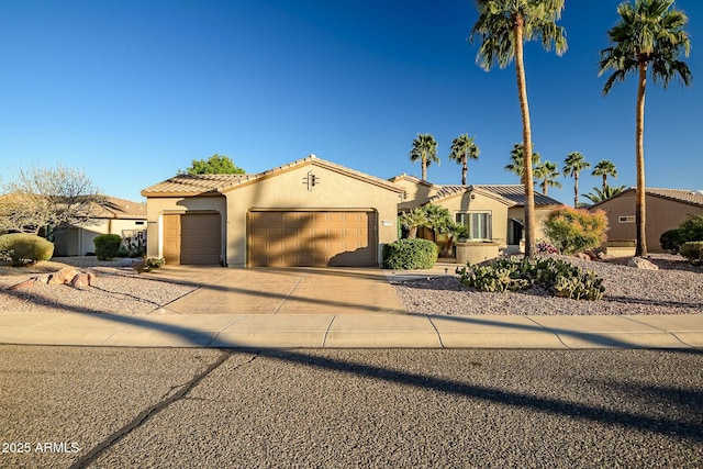 mediterranean / spanish-style house featuring stucco siding, a garage, concrete driveway, and a tile roof