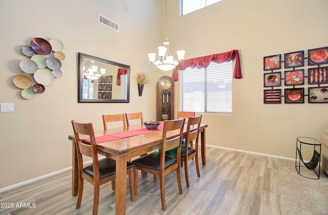 708 E Dry Creek Rd, San Tan Valley, AZ 85143 - dining room featuring a chandelier, light wood finished floors, healthy amount of natural light, and a towering ceiling