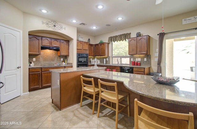 708 E Dry Creek Rd, San Tan Valley, AZ 85143 - kitchen with black appliances, decorative backsplash, under cabinet range hood, a kitchen bar, and recessed lighting