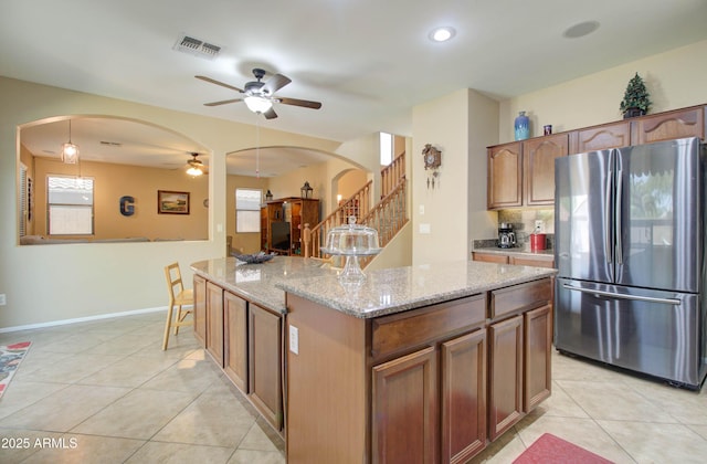 708 E Dry Creek Rd, San Tan Valley, AZ 85143 - kitchen with freestanding refrigerator, arched walkways, a ceiling fan, light tile patterned flooring, and light stone counters