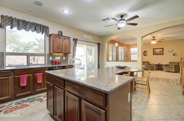 708 E Dry Creek Rd, San Tan Valley, AZ 85143 - kitchen featuring a ceiling fan, arched walkways, open floor plan, a center island, and light tile patterned floors