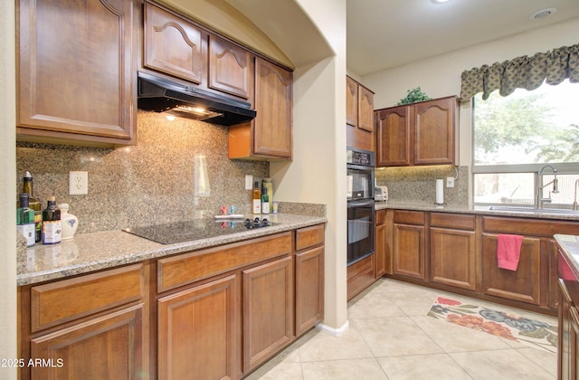 708 E Dry Creek Rd, San Tan Valley, AZ 85143 - kitchen featuring black appliances, under cabinet range hood, light tile patterned flooring, light stone countertops, and decorative backsplash