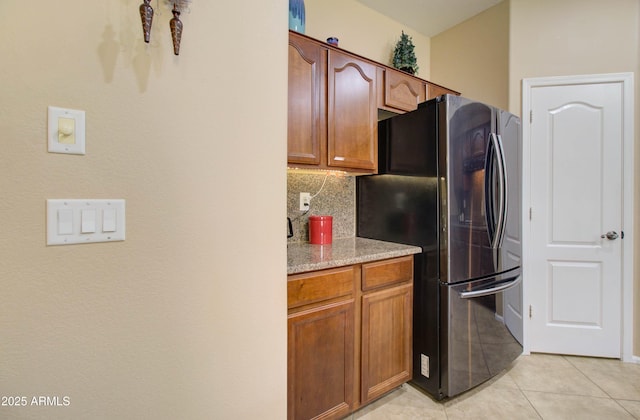 708 E Dry Creek Rd, San Tan Valley, AZ 85143 - kitchen featuring freestanding refrigerator, tasteful backsplash, light tile patterned flooring, and brown cabinets