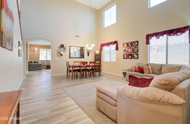 708 E Dry Creek Rd, San Tan Valley, AZ 85143 - living area featuring arched walkways, a high ceiling, light wood-type flooring, healthy amount of natural light, and a chandelier