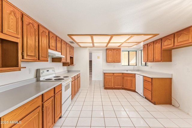 kitchen featuring under cabinet range hood, white appliances, a sink, visible vents, and brown cabinetry