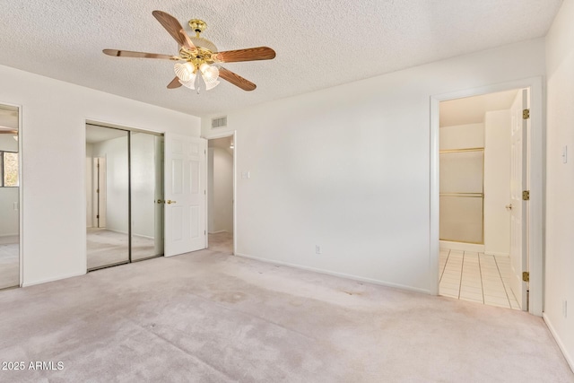 unfurnished bedroom featuring a textured ceiling, connected bathroom, visible vents, carpet, and two closets