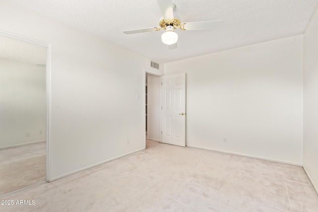 carpeted spare room with baseboards, ceiling fan, visible vents, and a textured ceiling