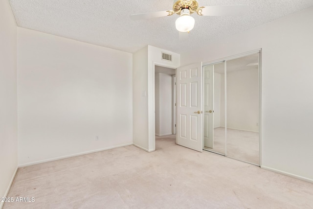 unfurnished bedroom with carpet, a closet, visible vents, a textured ceiling, and baseboards