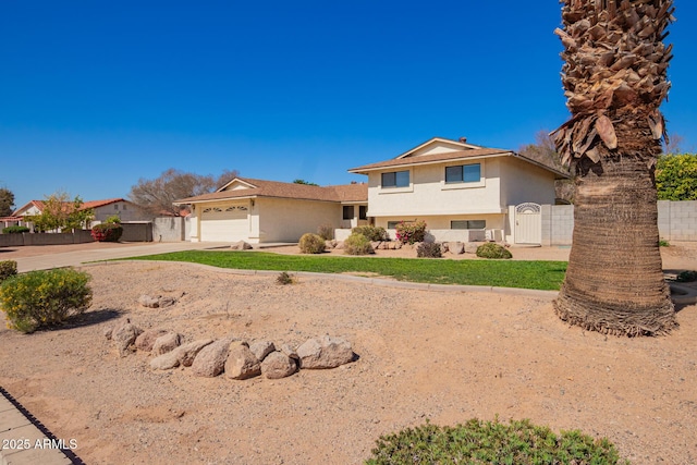 view of front of property featuring a garage, concrete driveway, a gate, fence, and stucco siding