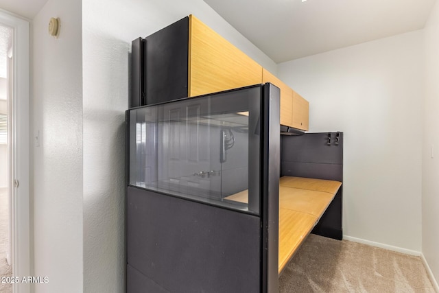 kitchen with carpet floors, light brown cabinets, light countertops, and baseboards