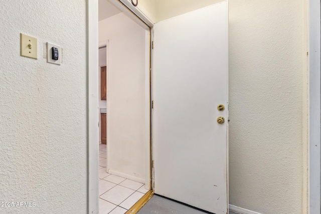 hallway with light tile patterned floors and a textured wall