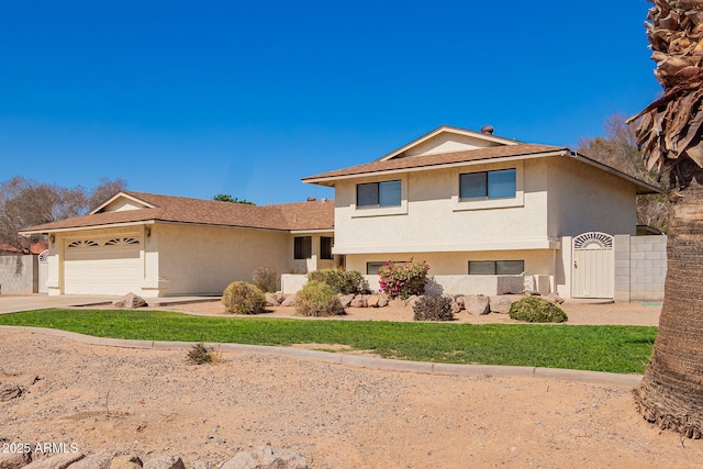 tri-level home with driveway, fence, an attached garage, and stucco siding