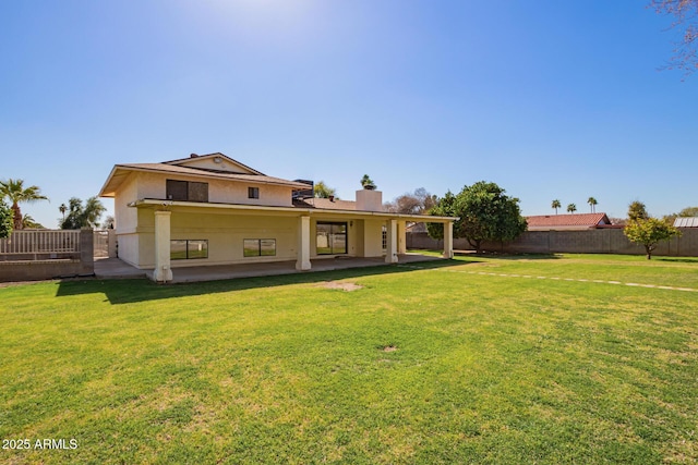 rear view of house with a patio, a lawn, a fenced backyard, and stucco siding