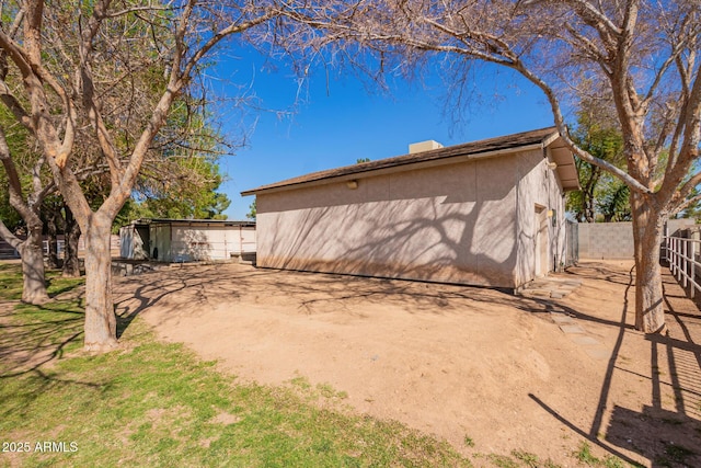 view of side of home with fence and stucco siding