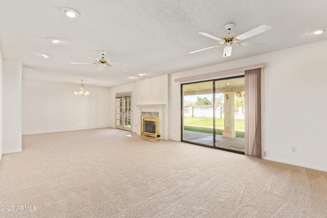 unfurnished living room featuring ceiling fan with notable chandelier, carpet floors, a textured ceiling, and a fireplace