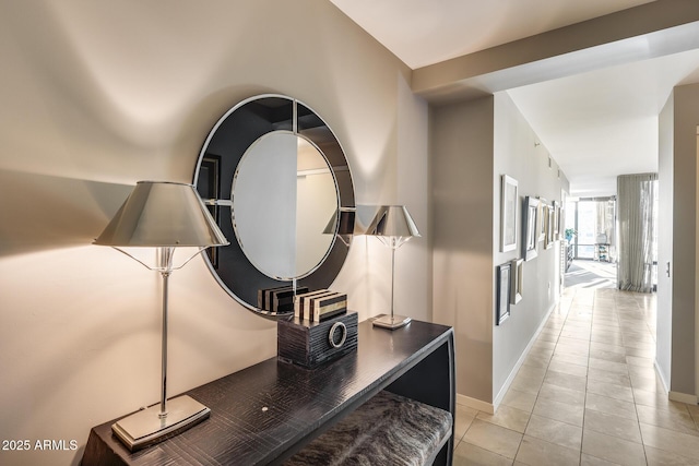 hall featuring baseboards and light tile patterned floors