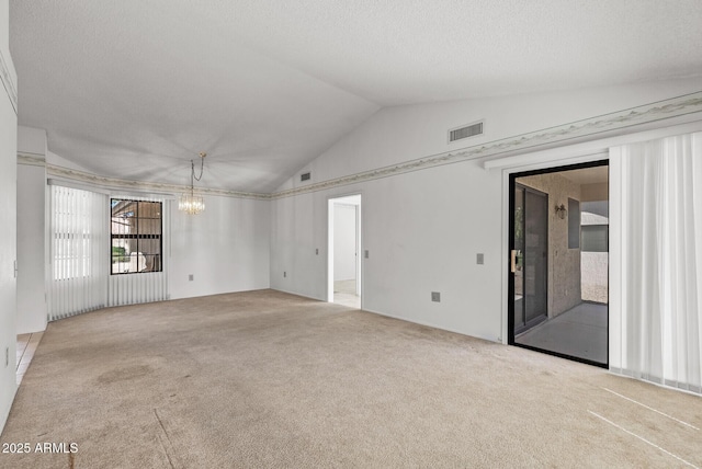 carpeted spare room featuring a textured ceiling, a notable chandelier, lofted ceiling, and visible vents