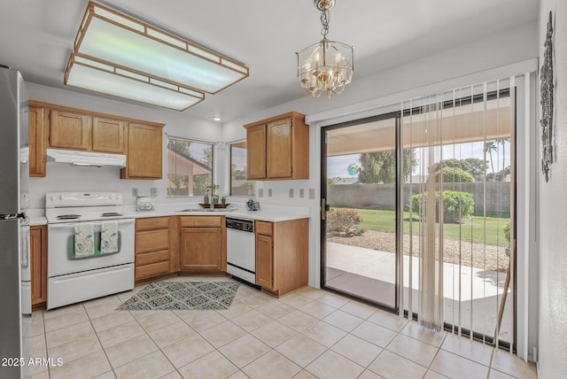 kitchen with a chandelier, white appliances, light countertops, under cabinet range hood, and a sink