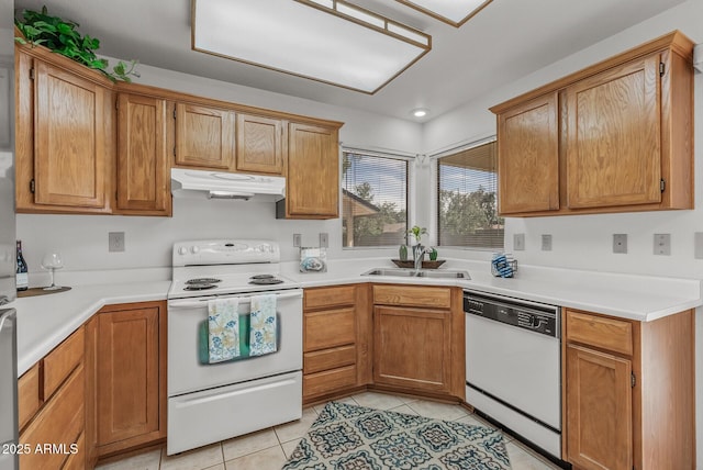 kitchen with a sink, light countertops, white appliances, under cabinet range hood, and light tile patterned flooring