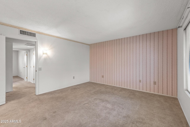 carpeted spare room featuring visible vents and a textured ceiling
