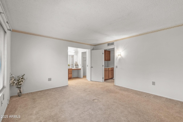 unfurnished living room featuring visible vents, light colored carpet, ornamental molding, and a textured ceiling