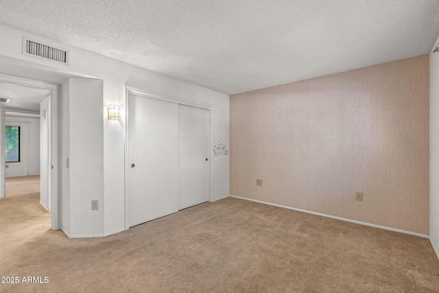 unfurnished bedroom featuring visible vents, baseboards, a closet, a textured ceiling, and carpet flooring