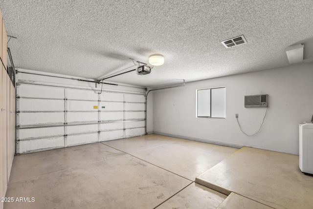 garage featuring a garage door opener, a wall unit AC, and visible vents