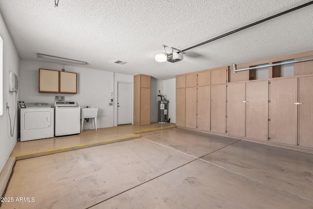 garage featuring independent washer and dryer, visible vents, water heater, a sink, and a garage door opener