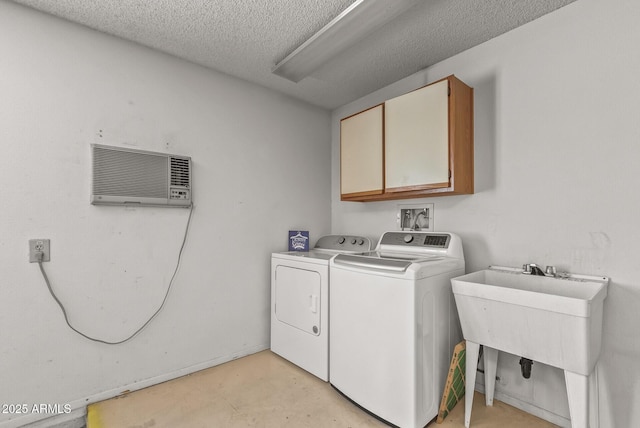 clothes washing area with separate washer and dryer, a wall mounted air conditioner, a textured ceiling, cabinet space, and a sink