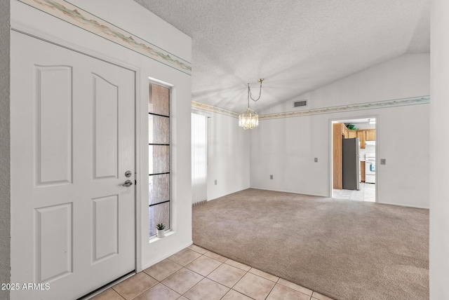 foyer featuring visible vents, light tile patterned floors, an inviting chandelier, light carpet, and lofted ceiling