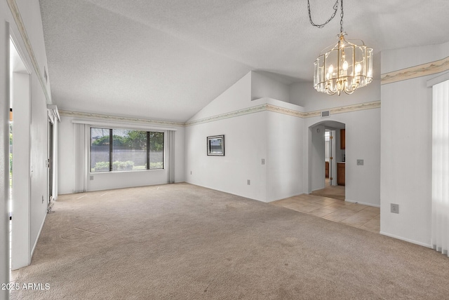 unfurnished living room featuring arched walkways, a textured ceiling, carpet floors, a chandelier, and lofted ceiling