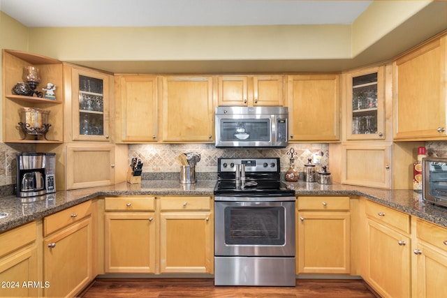 kitchen with dark hardwood / wood-style flooring, light brown cabinetry, dark stone counters, and appliances with stainless steel finishes