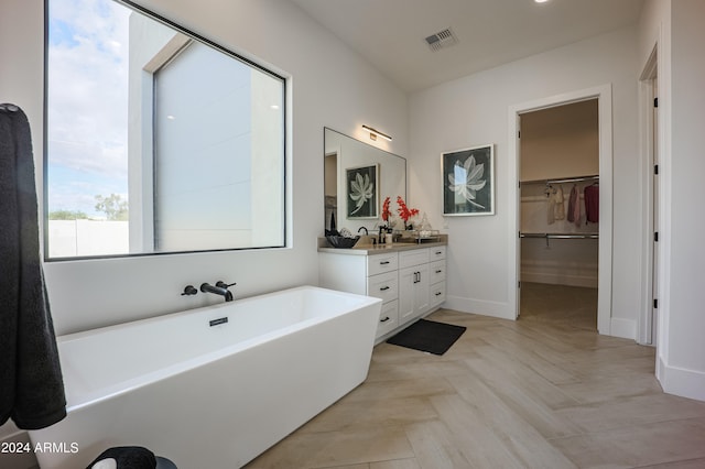 bathroom featuring a tub, vanity, and parquet floors