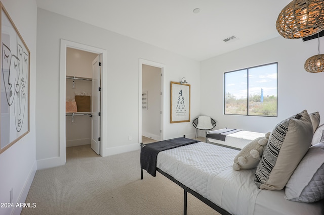 bedroom featuring a walk in closet, light carpet, and a closet