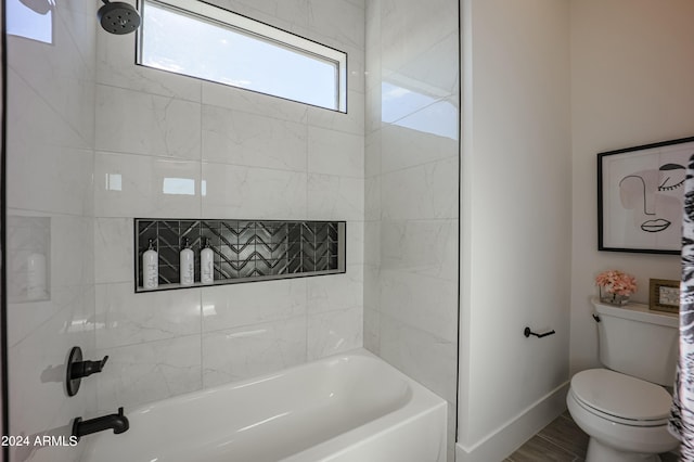 bathroom with toilet and tiled shower / bath