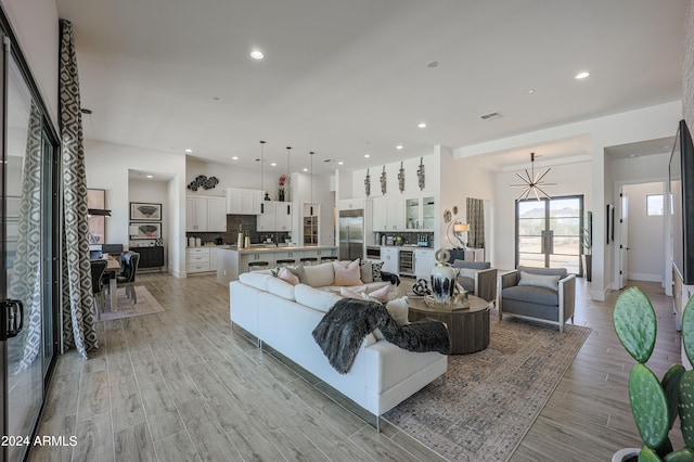 living room with wine cooler, light wood-type flooring, and a notable chandelier