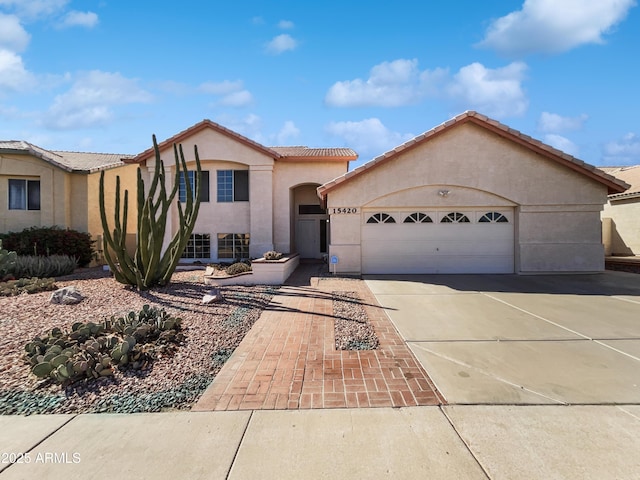 view of front of home with a garage, a tile roof, concrete driveway, and stucco siding