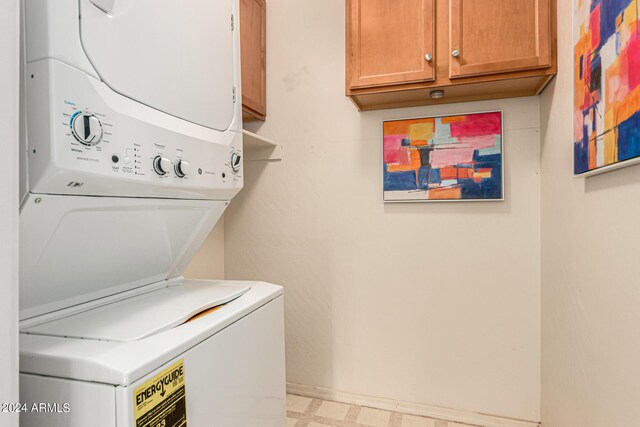 washroom with stacked washer and clothes dryer and cabinets