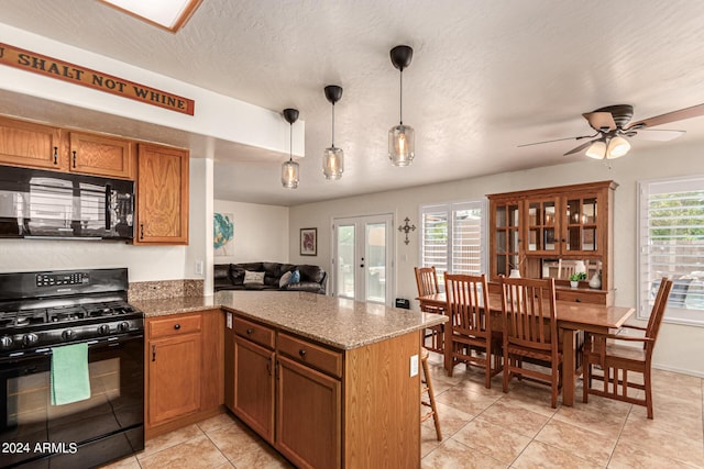 kitchen featuring dark stone countertops, pendant lighting, black appliances, kitchen peninsula, and french doors