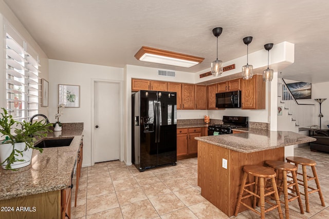 kitchen with kitchen peninsula, decorative light fixtures, dark stone countertops, black appliances, and sink