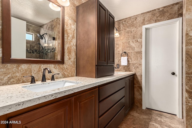 bathroom featuring a shower, tile walls, and vanity