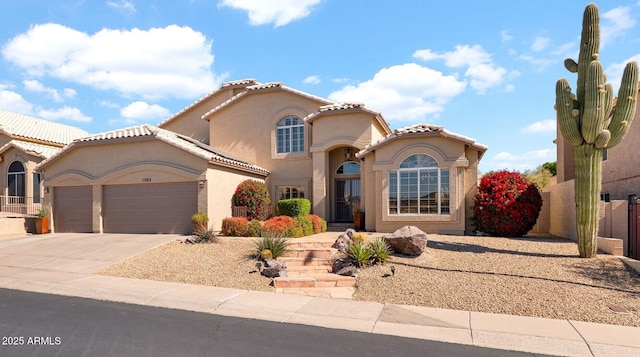 mediterranean / spanish-style house with a garage, a tiled roof, concrete driveway, and stucco siding