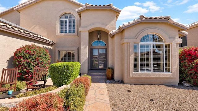 view of exterior entry featuring a tile roof and stucco siding